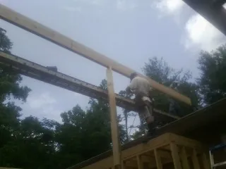 Carpenter setting a ridge beam over a new addition frame — Ice Dam Removal by Roofing Brothers in Bethany Beach