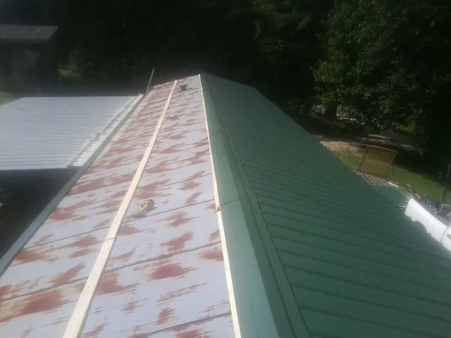 Old rusted panels beside newly installed green metal roofing — Wind Damage Roof Repair by Roofing Brothers in Bethany Beach