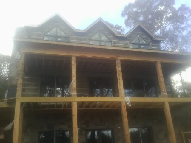 Dormers and porch framing on a large log home under construction — Roof Coating work by our crew in Bethany Beach
