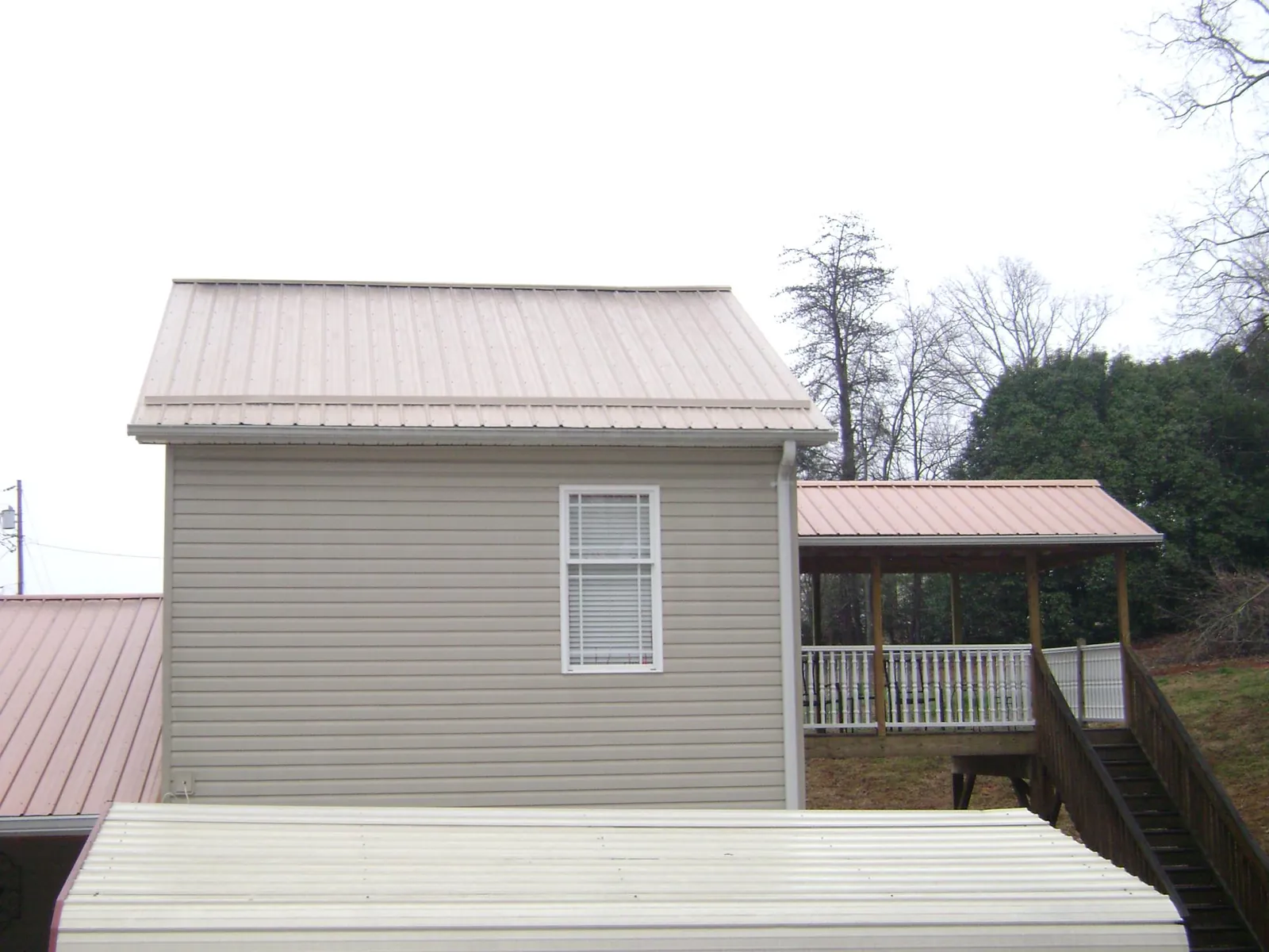 Tan metal roofs on a two story addition and attached porch, from a Roof Replacement job in Bethany Beach