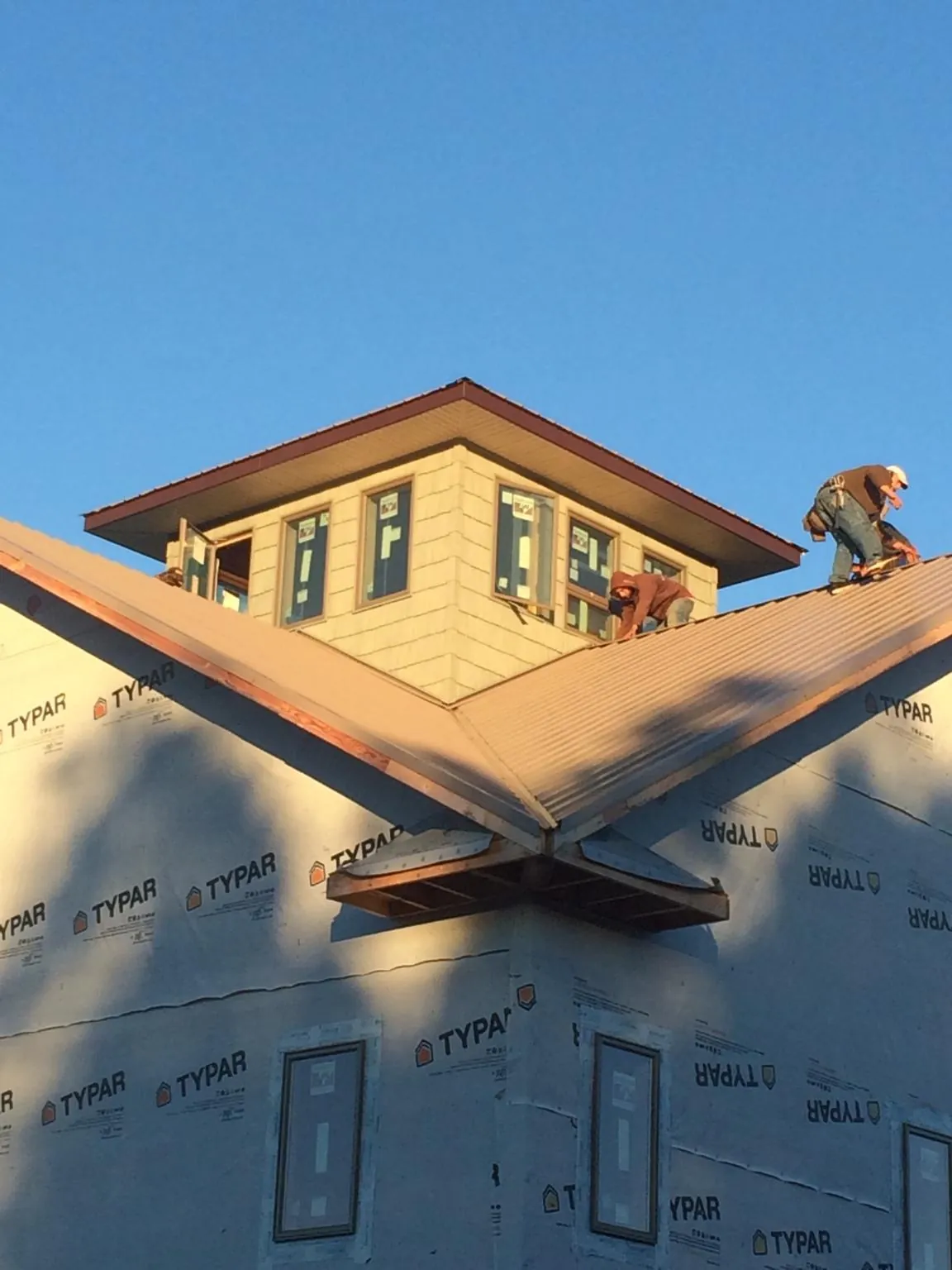 Roofers working around a rooftop cupola on a new metal roof at sunset — Roof Waterproofing in Bethany Beach by Roofing Brothers